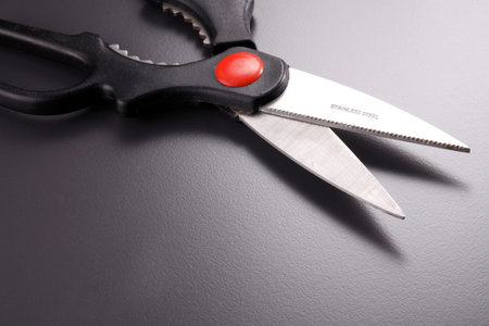 Open steel scissors with black plastic handles
