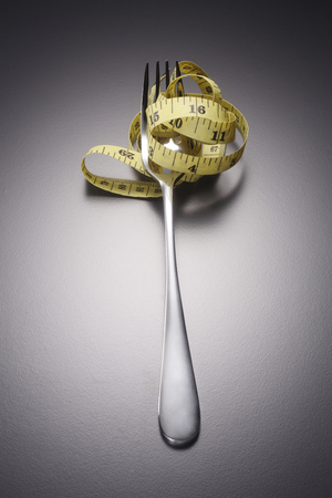 fork and measuring tape on the gray backgroundの写真素材