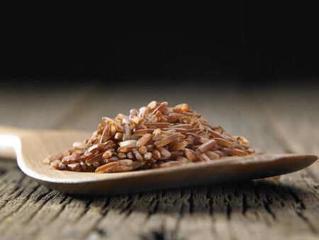 Raw brown rice in spoon on wooden backgroundの写真素材