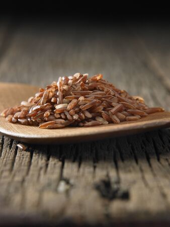 Raw brown rice in spoon on wooden backgroundの写真素材