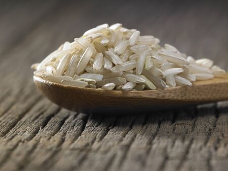 Raw brown rice in spoon on wooden backgroundの写真素材