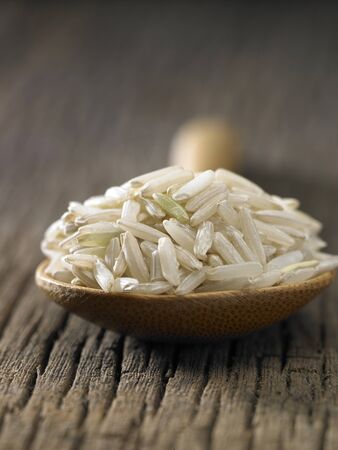 Raw brown rice in spoon on wooden backgroundの写真素材