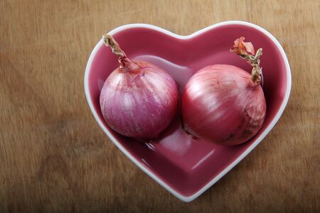 onions in a heart shaped bowlの写真素材