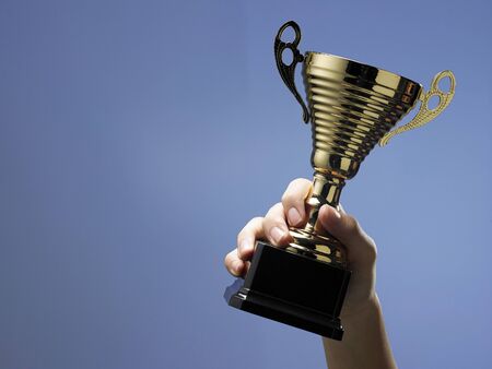 Man holding a champion golden trophyの写真素材