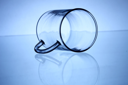 glass cup laid down on top of glass tableの写真素材