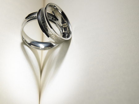 Wedding ring casting a heart-shaped shadow on the bookの写真素材