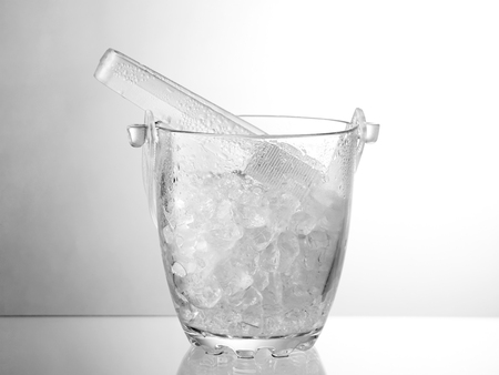 Glass ice bucket isolated on glass tableの写真素材