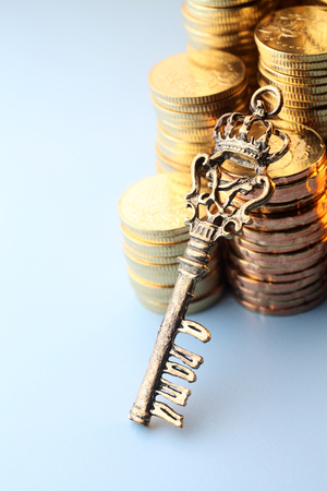 key resting on stack of coinの写真素材