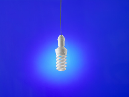 Illuminated light bulb on blue backgroundの写真素材