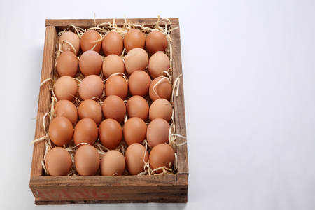bunch of fresh brown eggs and some straw in a wooden crateの写真素材