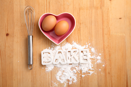 baking concept,hand whisk and eggs in a heart shape containerの写真素材