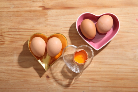 Brown eggs in heart shape transparent bowl on wooden background.の写真素材