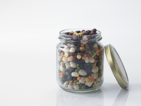 Mix bean of black eye peas, mung bean, adzuki beans, soy beans, black beans and red kidney beans in a mason jar over white backgroundの写真素材