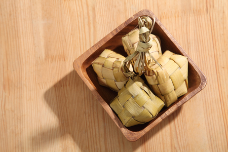 Ketupat (Rice Dumpling) On wooden Background. Ketupat is a natural rice casing made from young coconut leaves for cooking rice during eid Mubarakの写真素材