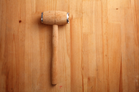 Hammer for beating the meat with a wooden handle isolated on wooden  backgroundの写真素材