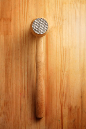 Hammer for beating the meat with a wooden handle isolated on wooden  background