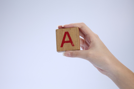 female's hand holding a wooden block with alphabet Aの写真素材