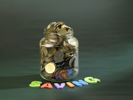 saving jar full of coins on chalk boardの写真素材