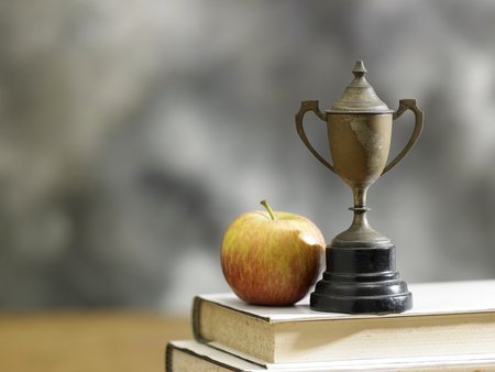apple on a stack of books with a trophyの写真素材