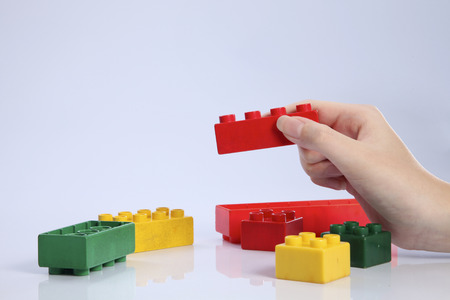 female hand holding a plastic building pieceの写真素材