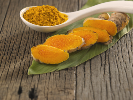 turmeric slices, powder and leaf on the wooden backgroundの写真素材