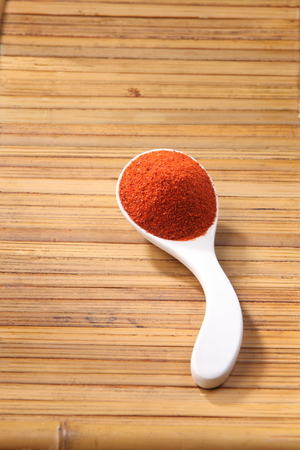 chili powder in a spoon on the bamboo backgroundの写真素材