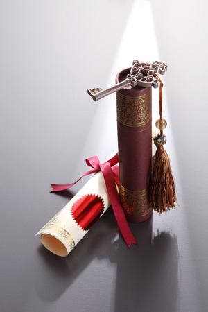 round certificate holder, certificate and key with tassel on the gray backgroundの写真素材