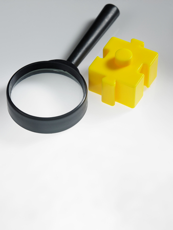 magnifier glass and a piece of yellow puzzleの写真素材