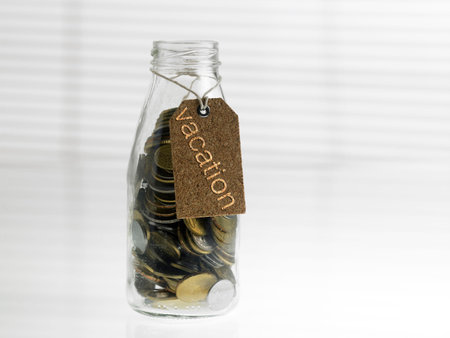 Concept image of personal finance, saving, investment. Coins in Glass jar with vacation Tag.
