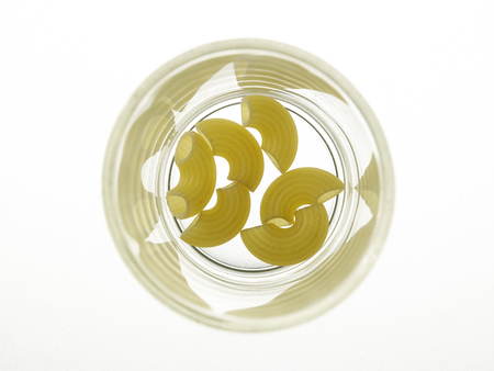macaroni pasta in a glass bow on the white backgroundの写真素材