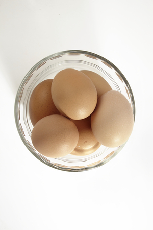 glass bowl full of chicken eggs on the white backgroundの写真素材