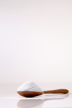 wooden spoon full of baking soda on the white backgroundの写真素材