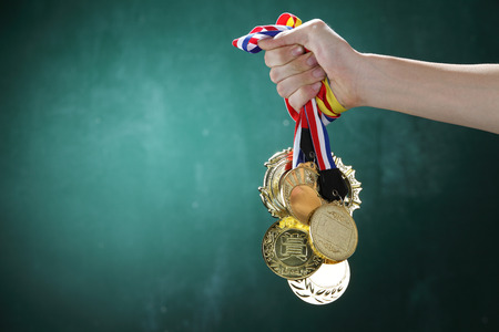 man holding a bunch of  medals in front of blackboardの写真素材
