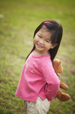 Girl holding teddy bear behind her backの写真素材