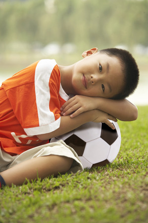 Boy lying on soccer ballの写真素材