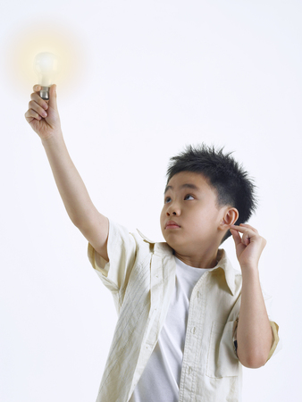 Boy holding a light bulb while snapping his fingersの写真素材