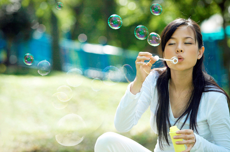 pregnant woman blowing bubbles in the parkの写真素材