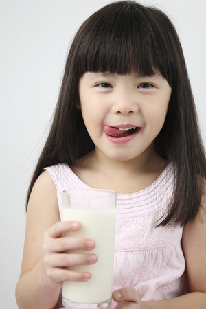 little chinese girl holding a glass of milkの写真素材