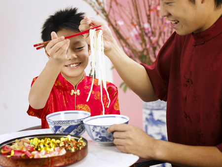 father and son eating longevity noodle during chinese new yearの写真素材