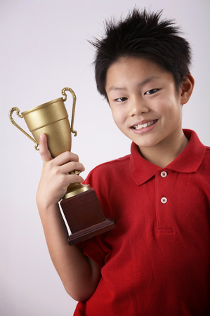 boy holding a trophy on the plain backgroundの写真素材