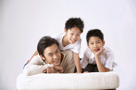 father and two sons arms around  on plain backgroundの写真素材