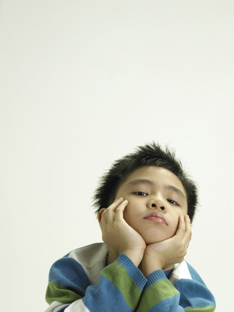 portrait of a boy with his hands under his chinの写真素材