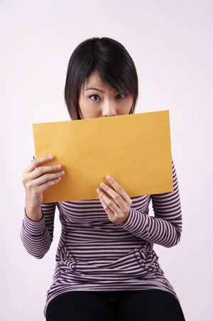 woman holding a card board on the plain backgroundの写真素材