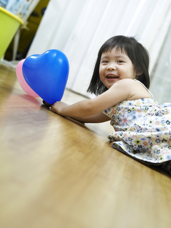 little laying on hte floor holding balloonsの写真素材