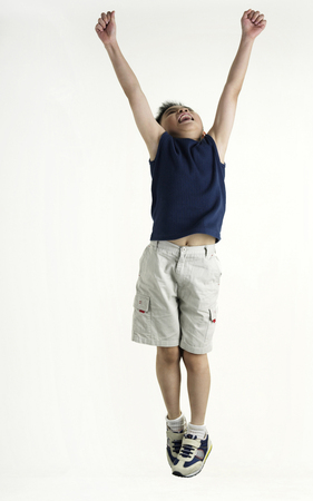 boy jump up with raising armの写真素材