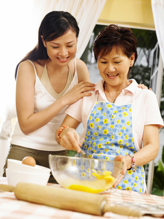mother teaching  daughter  to make make muffinsの写真素材