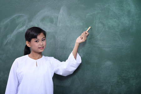 school girl with uniform pointing the black boardの写真素材