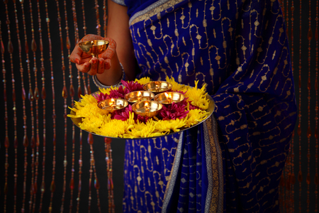 woman holding oil lamps and flower in a plateの写真素材
