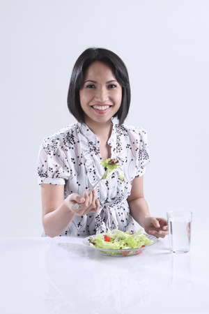 Woman eating salad, smilingの写真素材