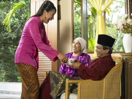 daughter in law serving tea for her parent in lawの写真素材